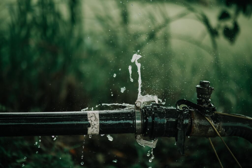Undichte Wasserleitung mit austretendem Wasser im Garten